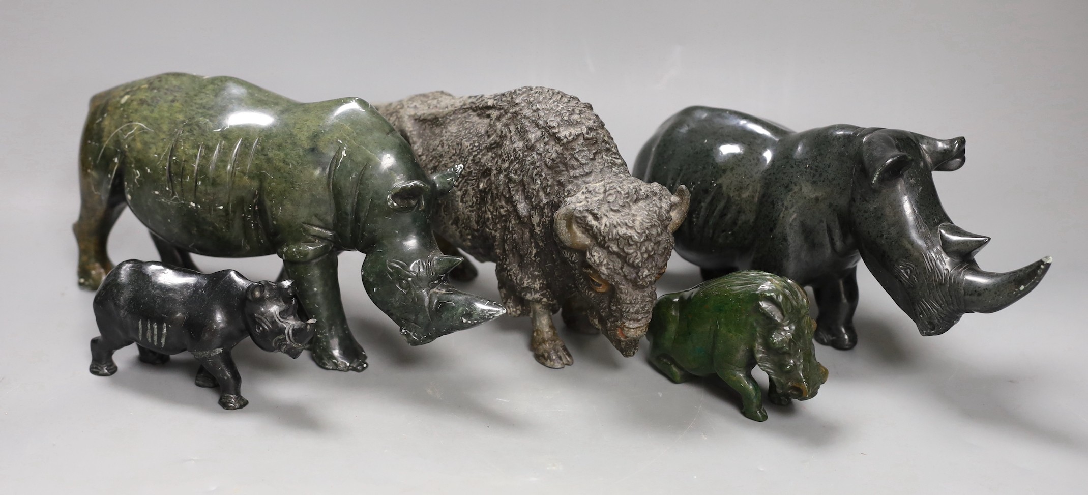 A selection of Zimbabwean animal carvings, to include, two carved Rhinos and two others and a spelter figure of a North American buffalo Tallest 14cm (5)